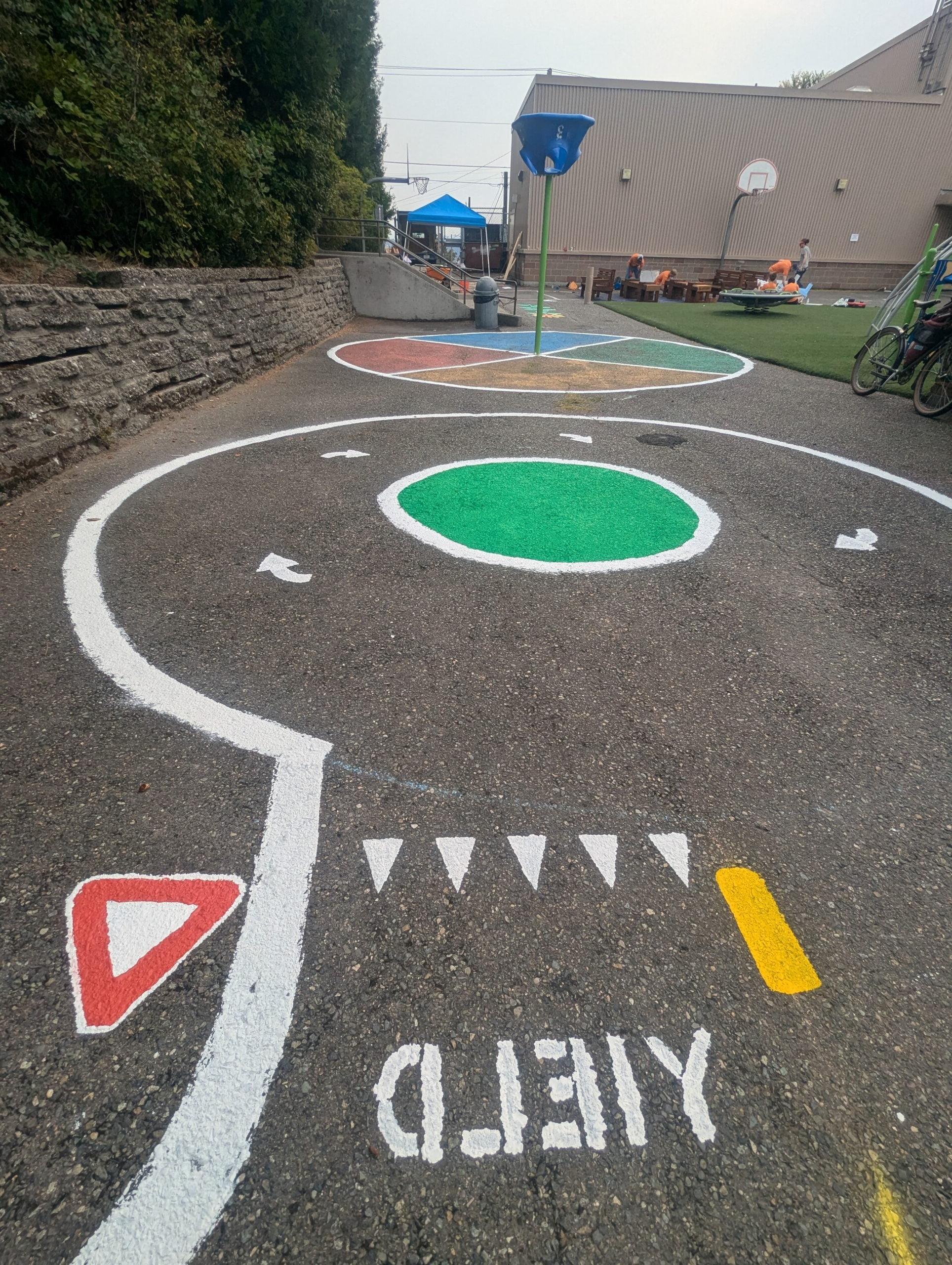 Miniature street painted with yield and roundabout.